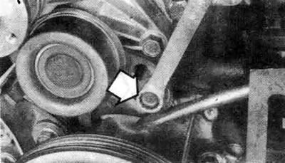 7.10а. Ослабьте болт натяжителя ремня (стрелка) и отведите натяжитель в сторону водяного насоса…