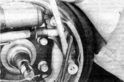 6.4е. Извлеките стяжную U-образную пружину из отверстий в тормозных колодках